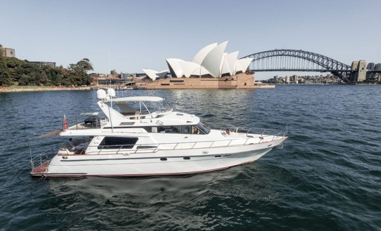 Lookouts in sydney: Motor yacht Enigma on calm harbour water with an opera house and steel arch bridge behind