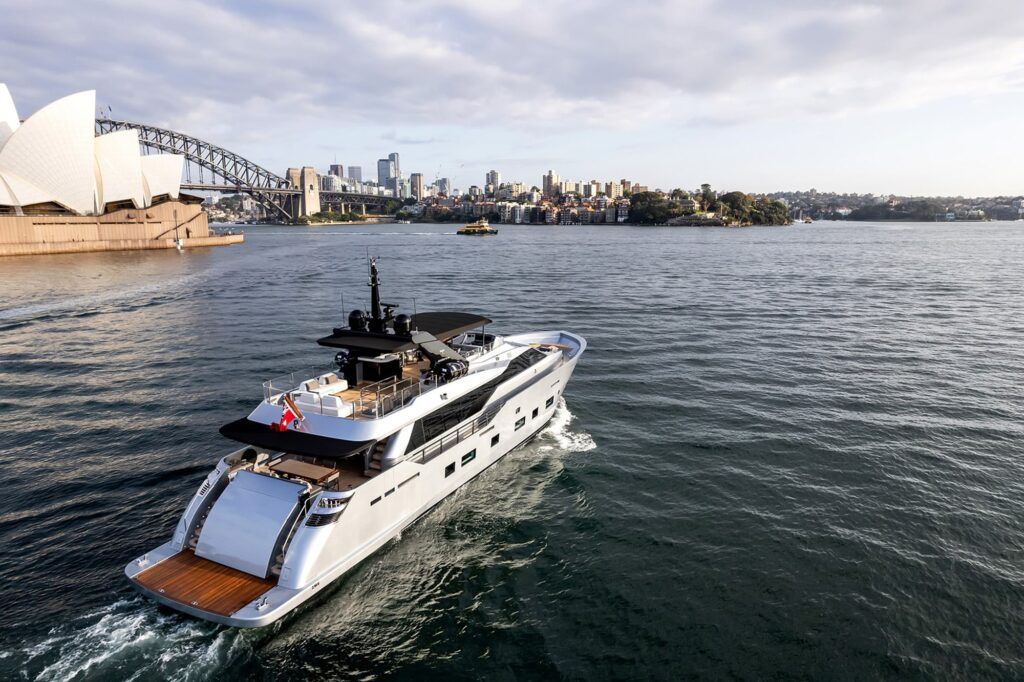 A sleek luxury yacht glides through the waters of Sydney Harbour, offering a stunning view of the iconic Sydney Opera House a