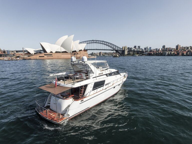 White motor yacht Enigma on harbour water with the Opera House and Harbour Bridge behind.