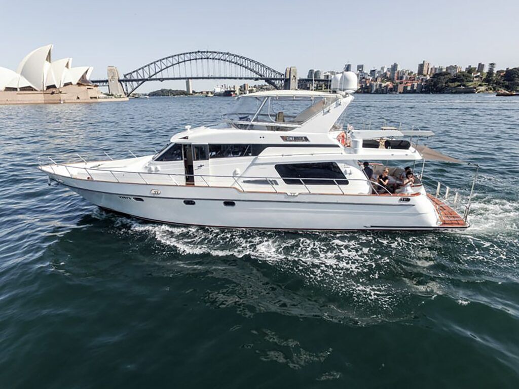 Pier 2: White flybridge motor yacht Enigma cruising on harbour water with an opera house and steel arch bridge behind
