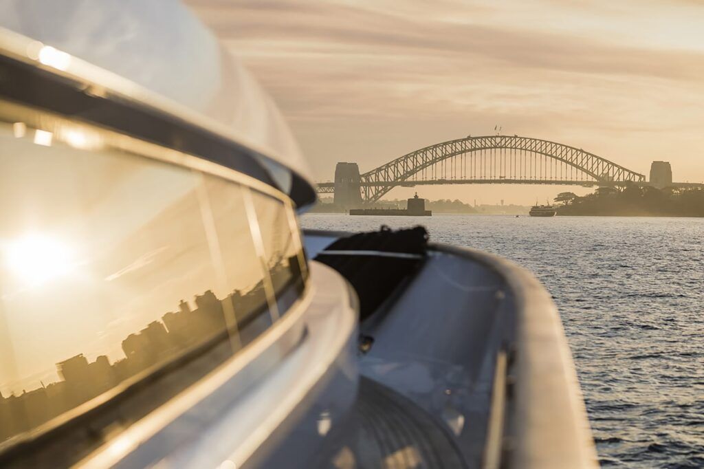View point near me: View along the side deck and tinted windows of the motor yacht Mohasuwei towards a steel arch bridge at