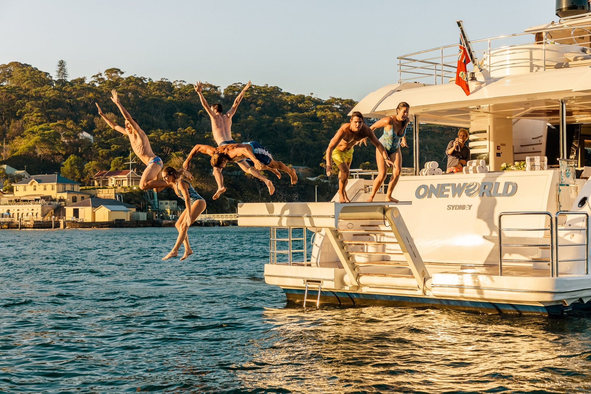 Six people leap from the swim platform of a motor yacht into calm harbour water