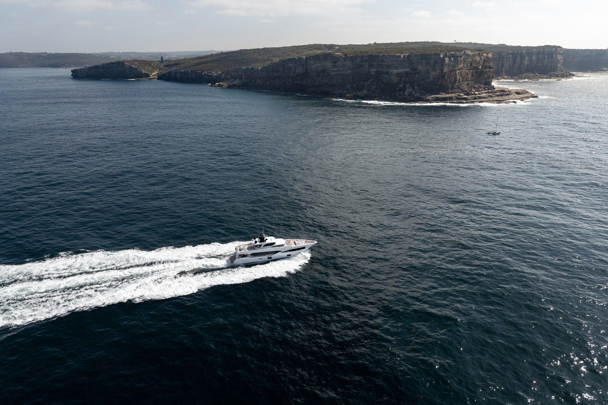Aerial view of the superyacht Oneworld cruising past sandstone sea cliffs