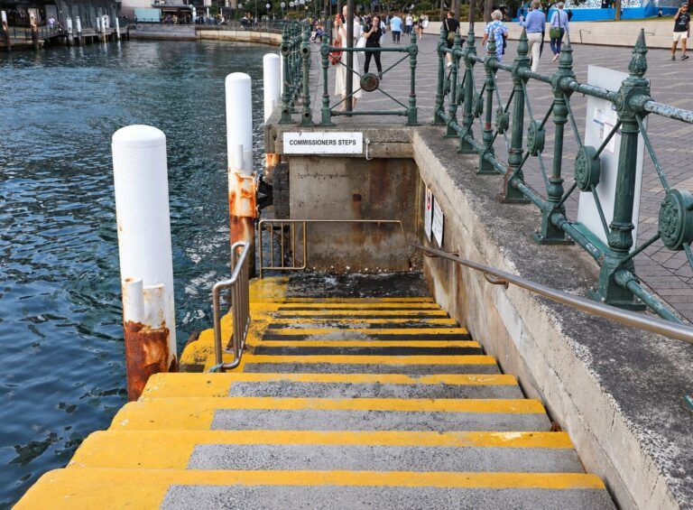 Concrete harbour steps with yellow nosings leading down to the water beside a sign reading Commissioners Steps.